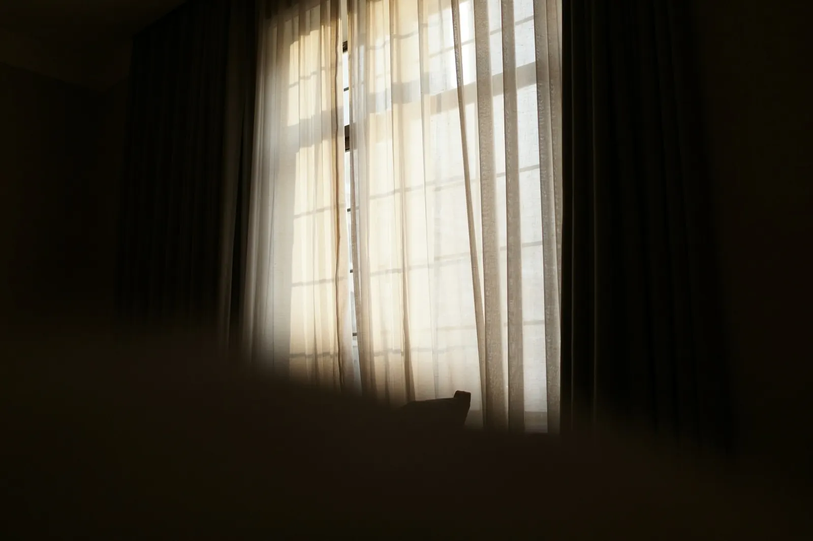 Sonnenlicht fällt durch transparente Gardinen in einem Wohnraum
